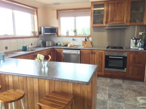 cocina con armarios de madera y encimera en Penguin Seaside Homestay en Penguin