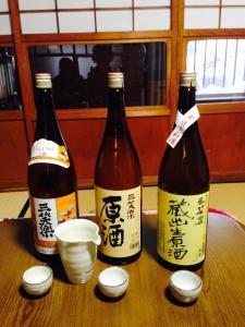 tres botellas de vino sentadas en una mesa en Guest House YAMASHITA-YA en Nanto