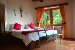 een slaapkamer met een bed met rode kussens en een raam bij La Montagne Guest Lodge in Hartbeespoort