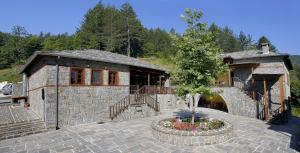 a stone building with a tree in front of it at Kerasies Guesthouse in Vovousa