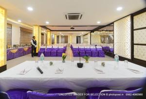 a table in a room with purple chairs and a man at Palm Galaxy in Itimādpur +45 photos