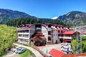 un grande edificio con auto parcheggiate in un parcheggio di Hotel Kanishka Manali - 200m from Mall Road a Manāli