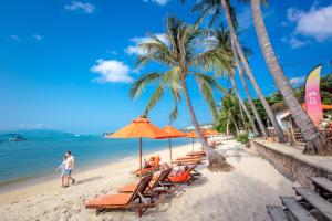 people sitting on a beach with chairs and umbrellas at Secret Garden Beach Resort in Bangrak Beach