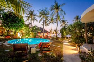 a swimming pool with two chairs and palm trees at Secret Garden Beach Resort in Bangrak Beach