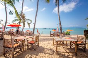 a beach with tables and chairs and the ocean at Secret Garden Beach Resort in Bangrak Beach