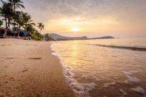 a beach with palm trees and the ocean at sunset at Secret Garden Beach Resort in Bangrak Beach