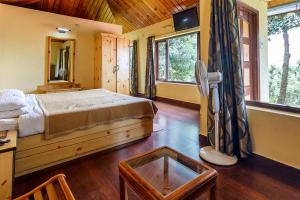 a bedroom with a bed and a desk and windows at Himalaya Darshan Resort in Kausani