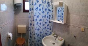 a bathroom with a blue and white shower curtain and a sink at Ivanka Apartment in Kaštela