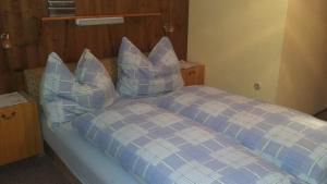 a bed with blue and white pillows on it at Ferienwohnung Waldhäusl in Sankt Martin bei Lofer