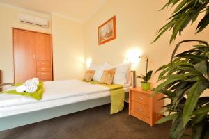 ナグヤタードにあるViktória Wellness Hotelのベッドルーム1室(ベッド1台、植物付)