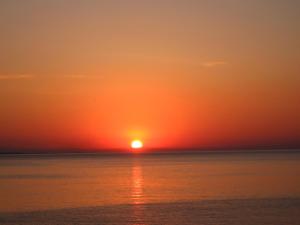 a sunset over the ocean with the sun in the sky at Hotel Villa Nisteri in Limenas