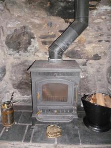 a stone fireplace with a stove in a room at Llugwy Cottage in Betws-y-coed