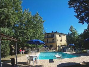 a swimming pool with chairs and umbrellas next to a building at La Francigena in Staggia
