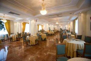 a banquet hall with tables and chairs and a chandelier at Hotel dei Platani in Nola