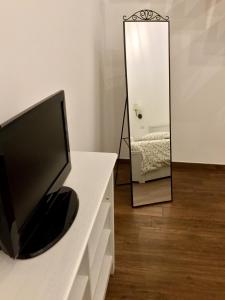 telewizor siedzący na komodzie przed lustrem w obiekcie B&B Sant'Agostino w mieście Giovinazzo