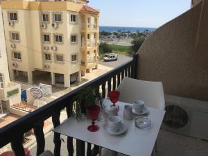 una mesa con tazas y platillos en el balcón en Pasithea Holiday Apartments en Lárnaca