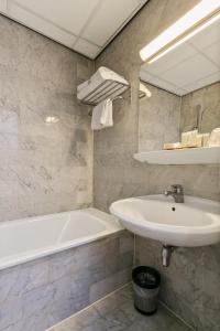 a bathroom with a white tub and a sink at Crown Inn in Eindhoven