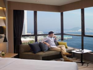 香港The Harbourview - Chinese YMCA of Hong Kong的坐在酒店房间沙发上的男人
