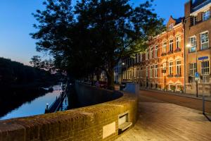 uma parede de tijolos ao lado de um canal com edifícios em CubaCasa em Den Bosch