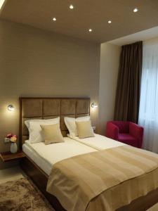 ベオグラードにあるAria Royal Nusic apartmentのベッドルーム1室(大型ベッド1台、赤い椅子付)