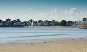 a view of a beach with houses in the background at Le Castel Marie Louise in La Baule