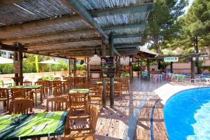 a patio with tables and chairs next to a swimming pool at Aparthotel Aquasol in Palmanova