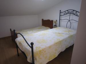 1 dormitorio con 1 cama con manta amarilla y blanca en casa d'Azoia, en Sesimbra