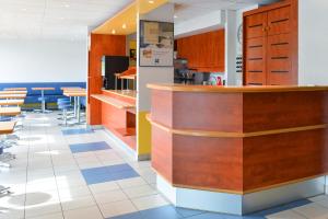 a kitchen with a counter and tables and chairs at Ibis budget Orléans Sud Comet in Orléans