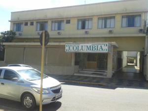 un coche aparcado frente a un edificio con un letrero en la calle en Hotel Columbia Palace en Pirassununga