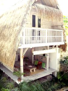 a house with a thatched roof and a porch at Uma Nandhi Ubud Natural Cottage in Tegalalang