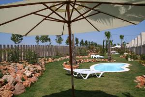 an umbrella in the grass next to a swimming pool at L' Escala Resort in L'Escala