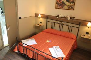 a bedroom with a orange bed with two books on it at Albergo Benito in Norcia