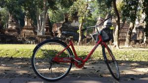 a red bike parked in front of a temple at Vitoonguesthouse2fanrooms & Aircondition in Sukhothai