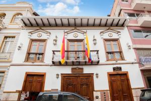 un edificio con dos banderas delante en Felicia Hotel & Suites, en Cuenca