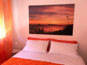 a bed with two white pillows and a painting above it at Sole e Luna in Trapani