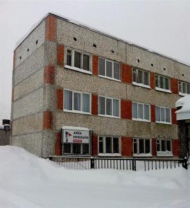 ein großes Backsteingebäude mit einem Schild davor in der Unterkunft Hostel Akka Knibekaize in Kirowsk
