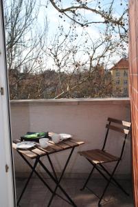 un tavolo e sedie su un balcone con finestra di Szamóca Apartman a Szeged