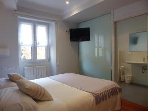 a bedroom with a bed with a television on the wall at Pensión Iribar in Getaria