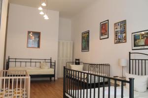 a room with two cribs and a bed and pictures on the wall at Hotel Pension Waizenegger am Kurfürstendamm in Berlin