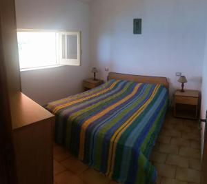 a bedroom with a bed with a colorful striped blanket at Casa fiorina a Capo vaticano in Capo Vaticano