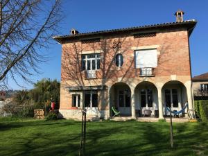 ein großes Backsteinhaus mit einem Rasenhof in der Unterkunft Chez Dan et Véro - Chambre d'hôte in Moissac