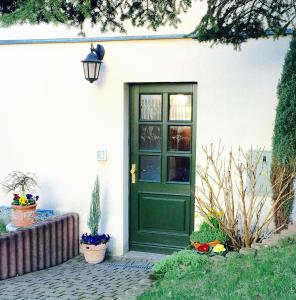 une porte verte sur une maison blanche ornée de fleurs dans l'établissement Ferienwohnung Ulbrich, à Neustadt in Sachsen