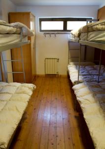 a room with three bunk beds and a wooden floor at Albergue Montes de Anaga in El Bailadero