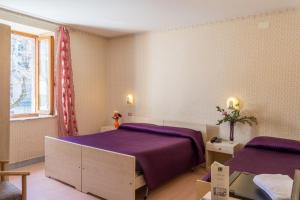 - une chambre avec un lit violet et une fenêtre dans l'établissement Hotel Italia Abbadia, à Abbadia San Salvatore