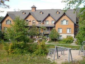 een groot huis met een tennisbaan ervoor bij Les Manoirs by Rendez-Vous Mont-Tremblant in Mont-Tremblant