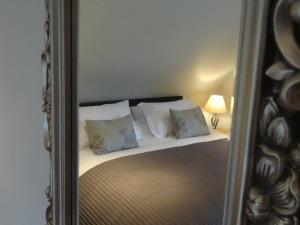 a mirror reflecting a bed with pillows on it at Coach House at The Glen in Helensburgh