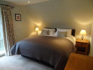 a bedroom with a large bed with two lamps at Coach House at The Glen in Helensburgh
