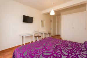 a room with a purple bed with two tables and a tv at Hostal Sol y Miel in Benalmádena