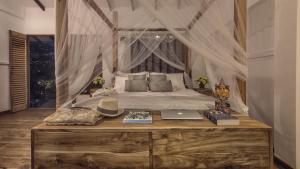 a bedroom with a canopy bed with a laptop on a table at C Beyond Nilaveli in Nilaveli