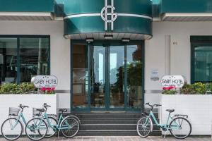 drei Fahrräder, die vor einem Gebäude geparkt sind in der Unterkunft Hotel Gaby in Rimini